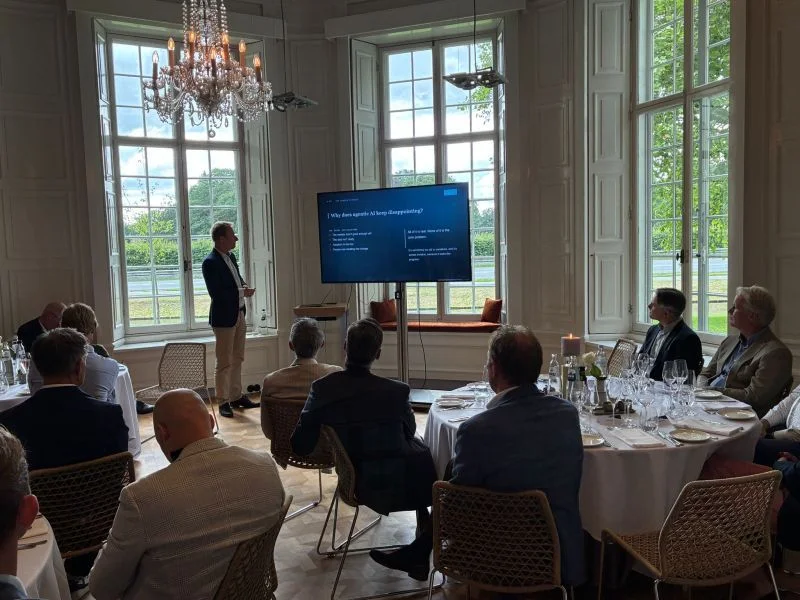 Rik leading a discussion with executives seated around tables.
