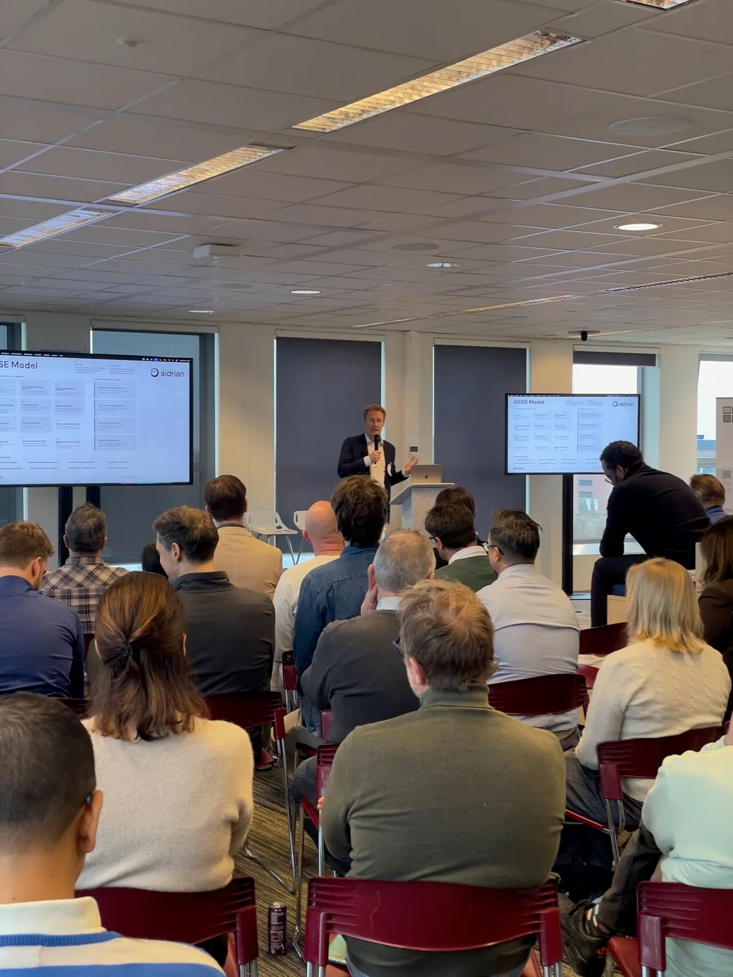 Rik presenting the Aidrian ARISE model to a seated audience.